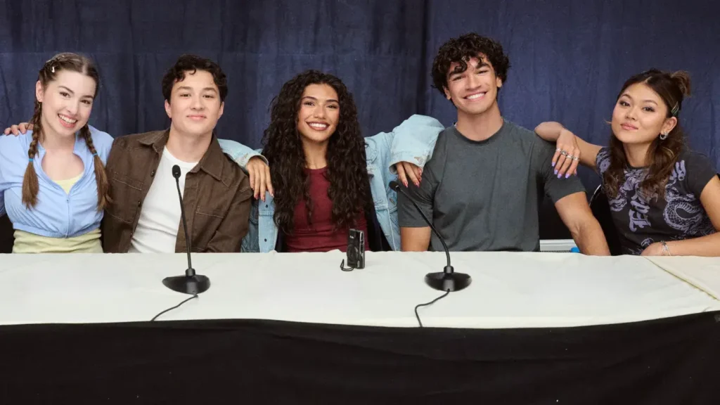 Five cast members of Hidden Heroes: A Descendants Story sitting side-by-side at a panel table and smiling for the camera.