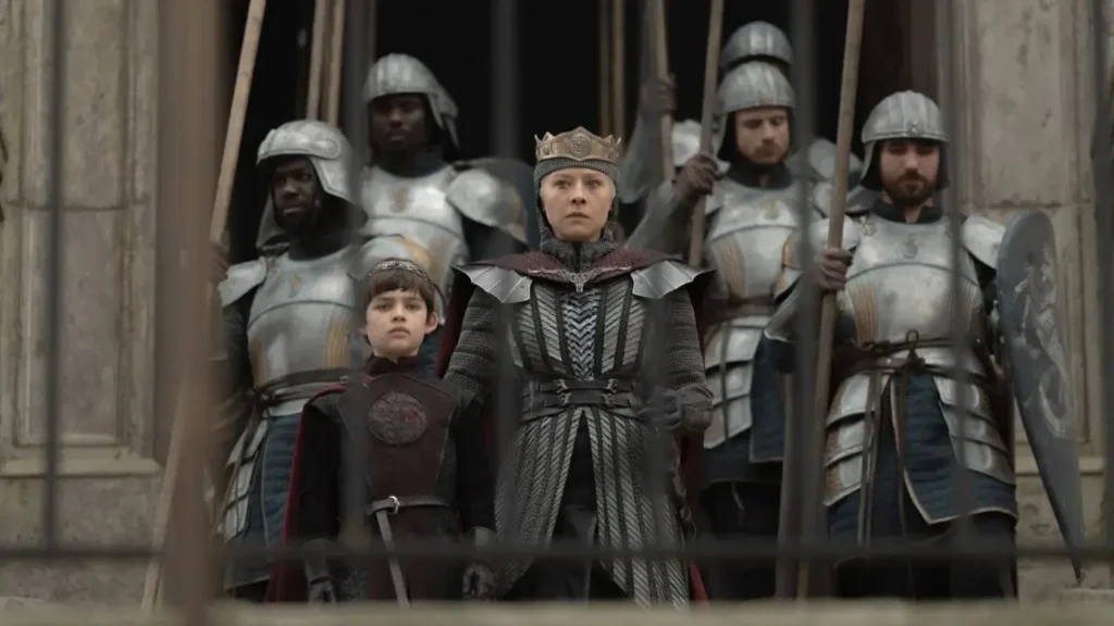 House of the Dragon Season 3 Finale Transports The Dance of the Dragons to a Far More Sinister Realm Emma D'Arcy as Queen Rhaenyra Targaryen standing with her young son Aegon and armored Velaryon guards in House of the Dragon.