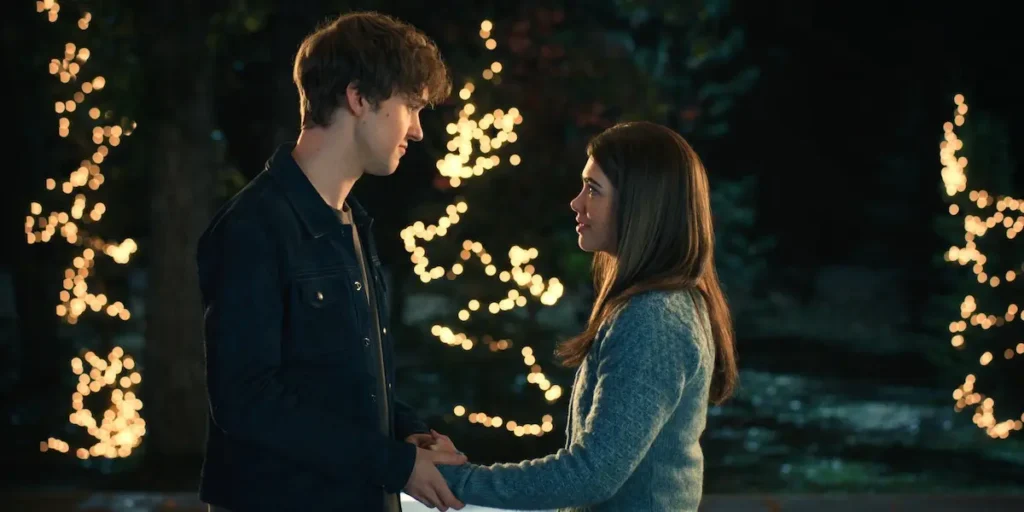 Connor Stanhope as Danny Walter and Alisha Newton as Erin holding hands under string lights in My Life With the Walter Boys.