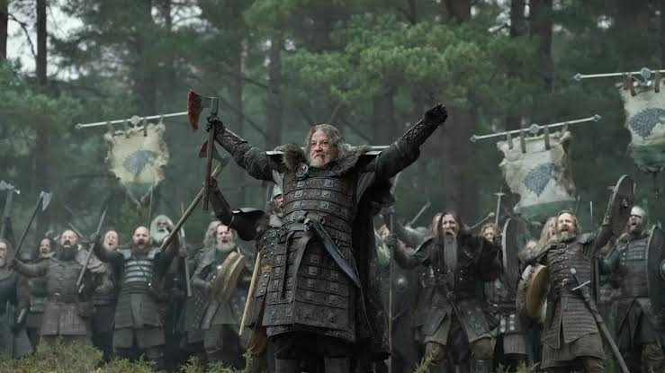 Lord Roderick Dustin raising a bloodied battle axe surrounded by Northmen soldiers in House of the Dragon.