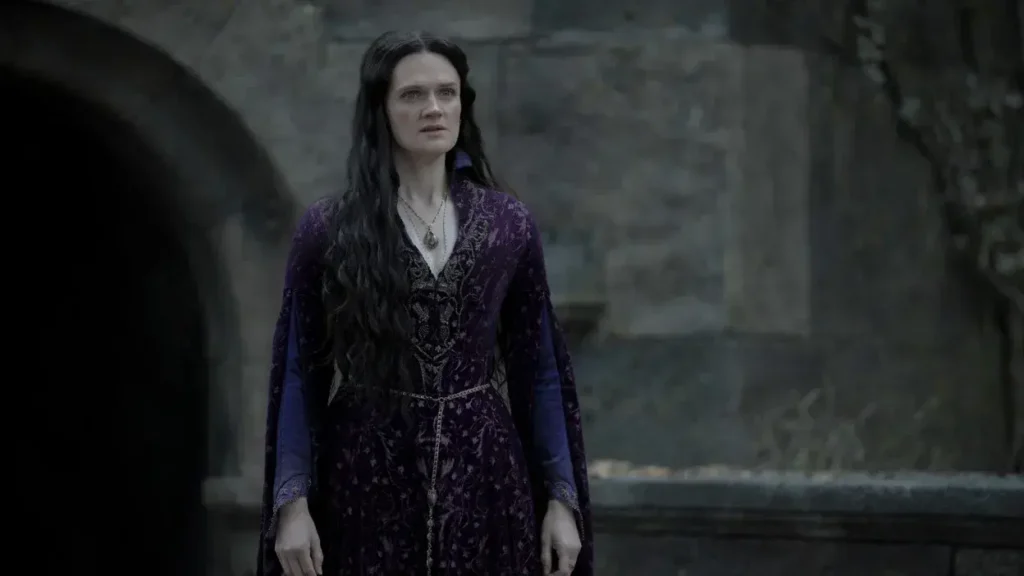 Gayle Rankin as Alys Rivers standing outdoors in an embroidered purple gown in House of the Dragon.