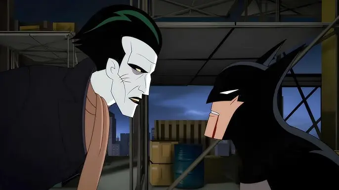 Animated Joker with pale skin, green hair, and a tan scarf standing over a bruised, bleeding Batman on a rooftop in Batman: Caped Crusader.