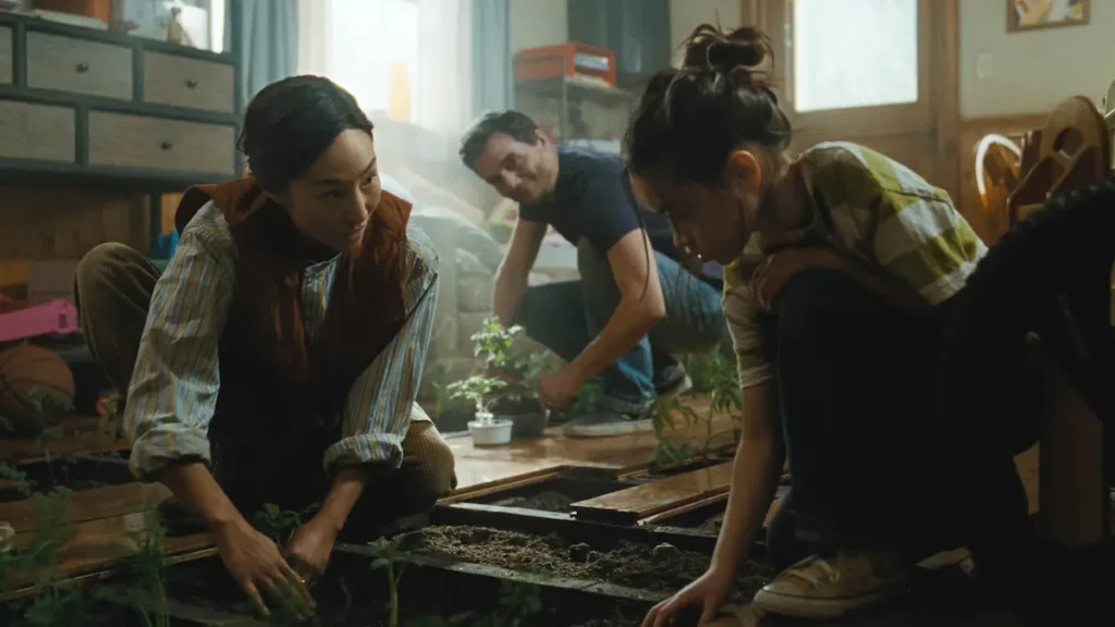 Greta Lee and family planting indoor crops through floorboards in The Last House.