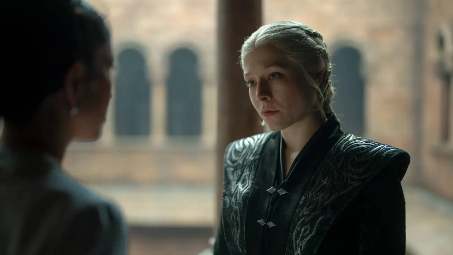 Emma D'Arcy as Queen Rhaenyra Targaryen with braided platinum hair looking intently at Mysaria in House of the Dragon.