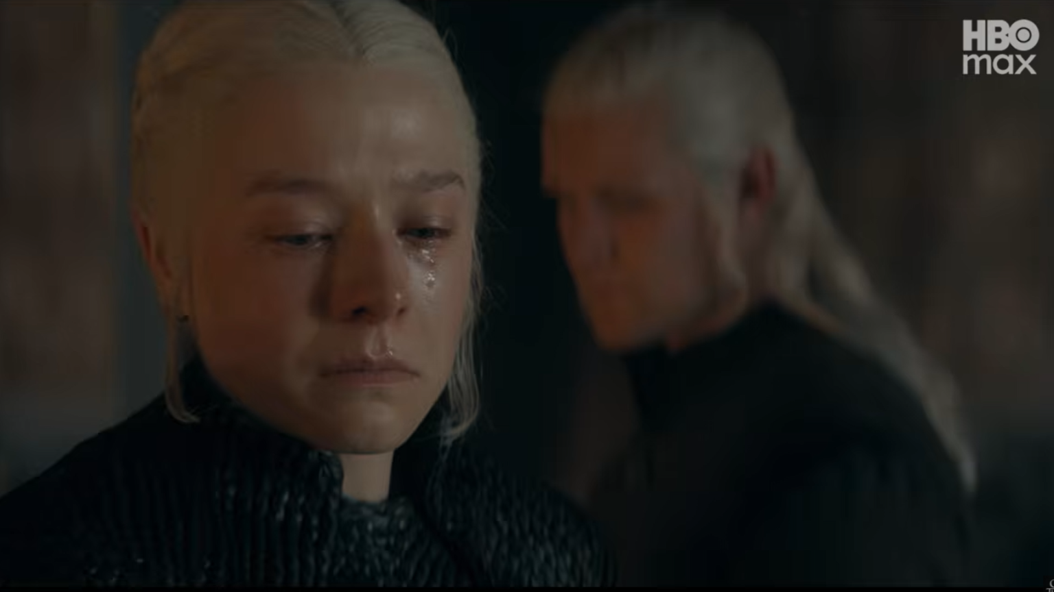 Emma D'Arcy as Queen Rhaenyra Targaryen crying with tears on her face while Matt Smith as Daemon Targaryen stands out of focus behind her in House of the Dragon.