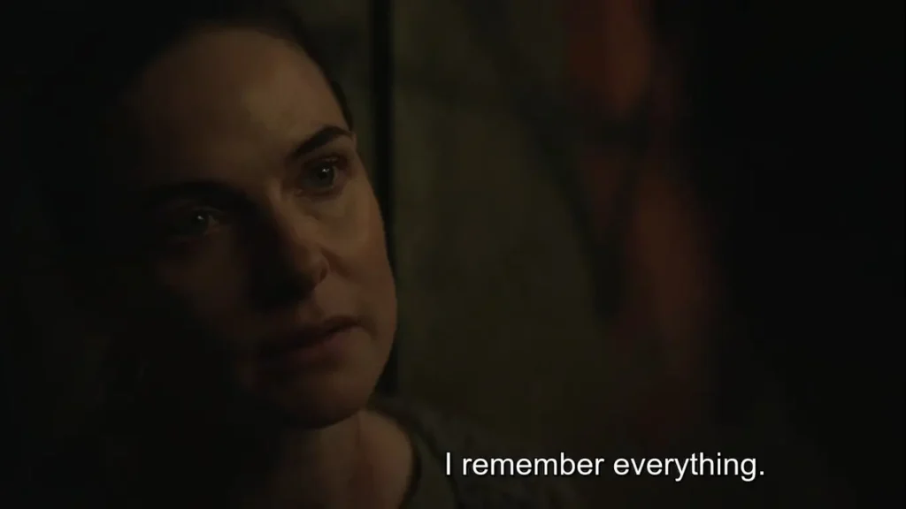 Close-up of Rebecca Ferguson in dim lighting with white subtitle text reading "I remember everything." in Silo.