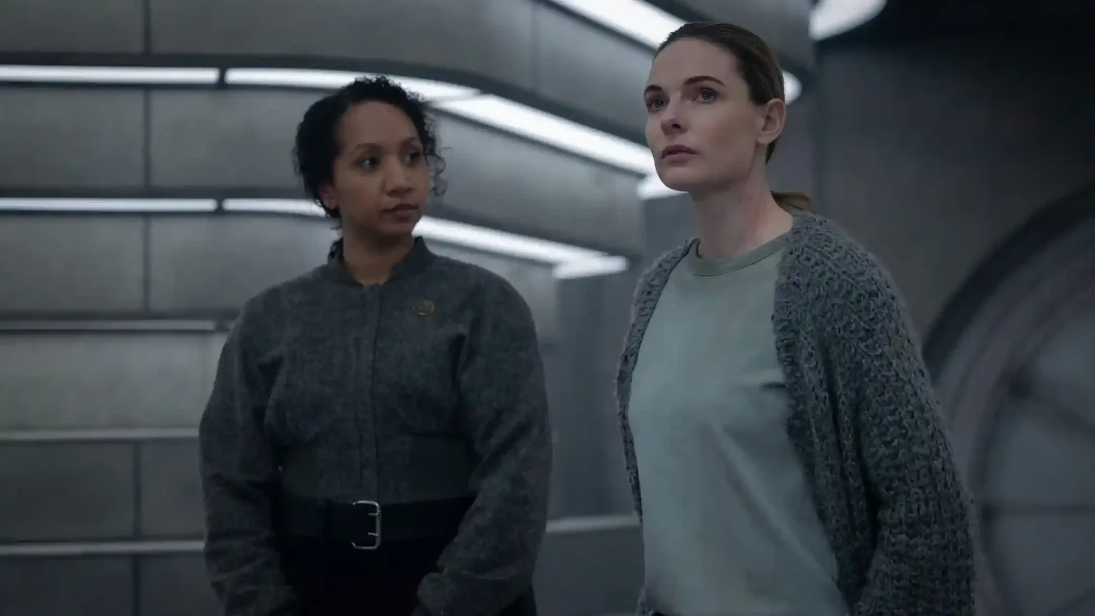 Silo Season 3 Episode 6 Recap & Ending Explained: What Does Senator Thurman’s Mysterious Offer Really Mean? Rebecca Ferguson and Remmie Akiuele standing in a sci-fi metallic corridor with intense expressions in Silo.