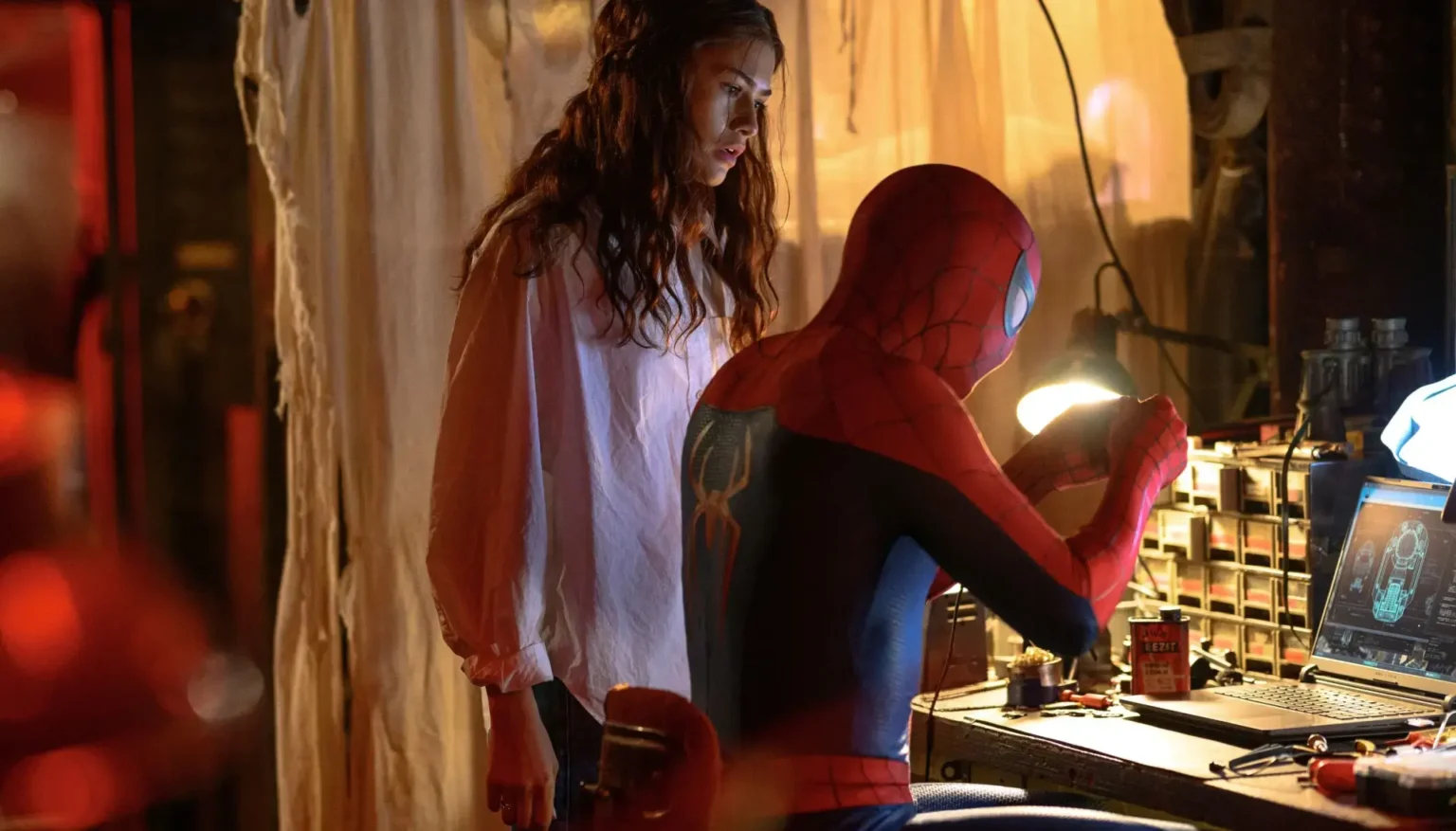 Zendaya as MJ watching Tom Holland as Spider-Man work on tech at a lit workshop desk in Spider-Man: Brand New Day.