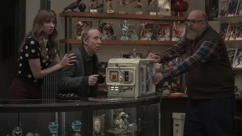 Lauren Lapkus, Kevin Sussman, and Brian Posehn reacting nervously around a complex sci-fi machine inside a comic book shop.