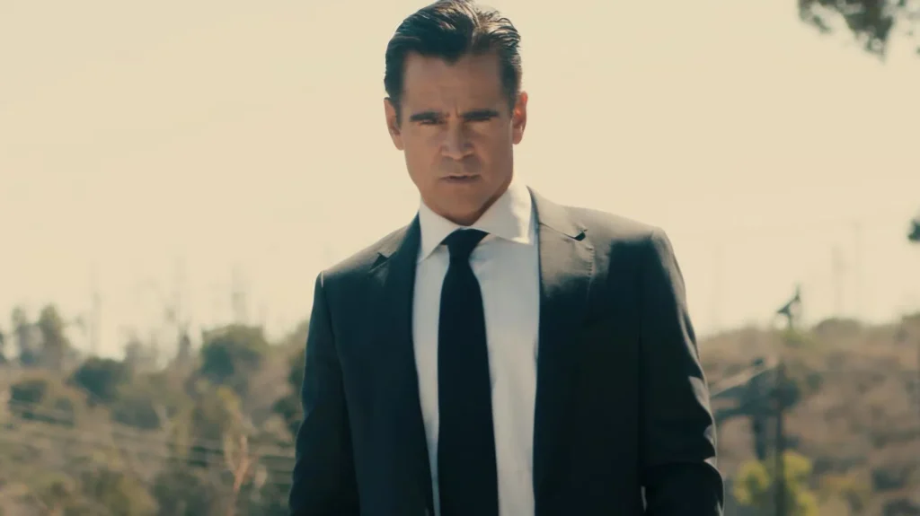 Colin Farrell walking forward outdoors in a suit and tie with a serious expression in Sugar.