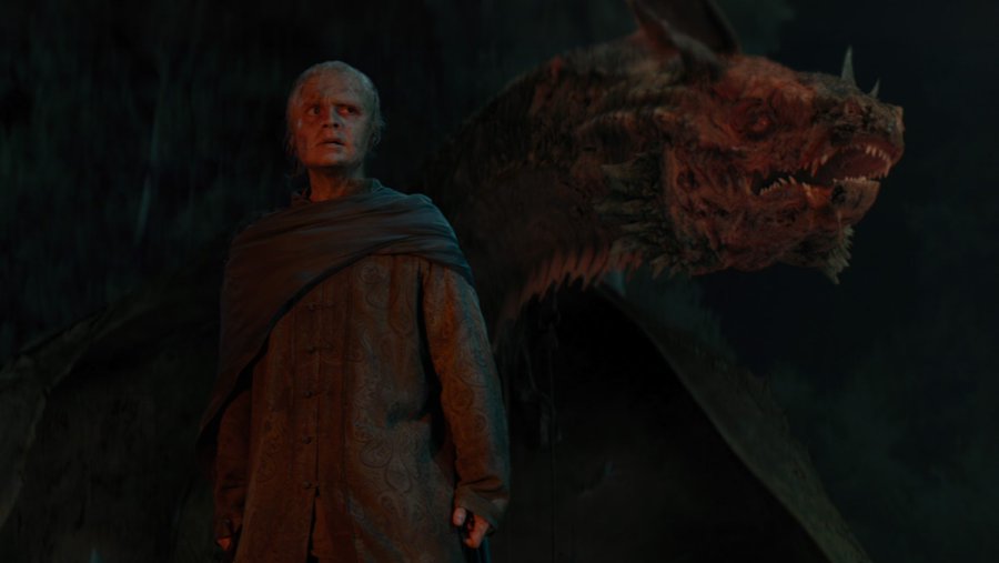 Tom Glynn-Carney as Aegon II Targaryen standing in front of his scarred dragon Sunfyre in House of the Dragon.