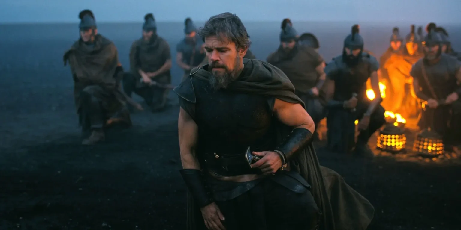 The Odyssey: Where Does Odysseus Go in the End? Christopher Nolan’s Finale and the Shadow of Dante Alighieri Matt Damon as Odysseus kneeling on a dark shoreline surrounded by Greek soldiers and fire in Christopher Nolan's The Odyssey.