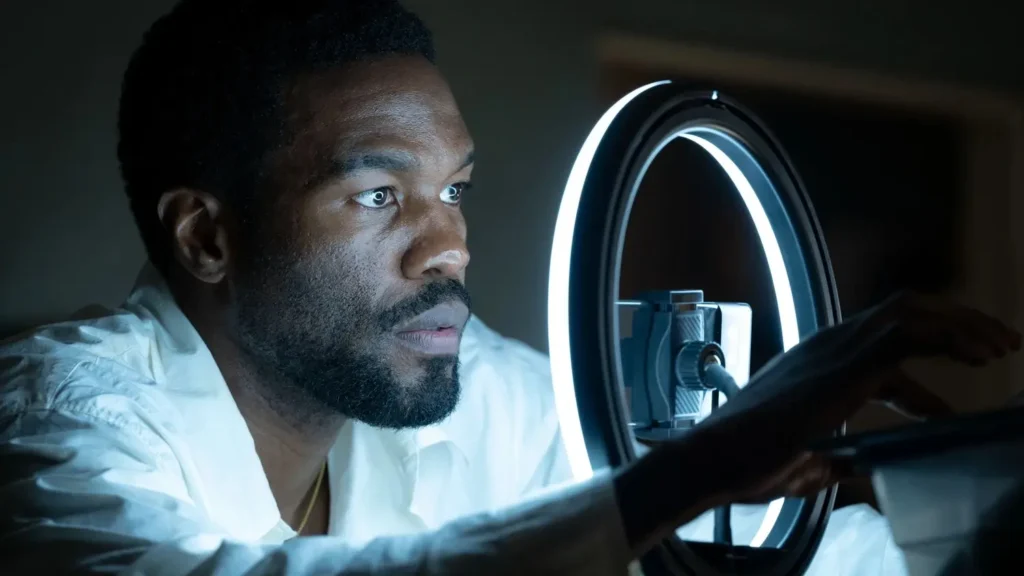 Yahya Abdul-Mateen II as Simon Williams looking intently past a glowing ring light in Marvel's Wonder Man.